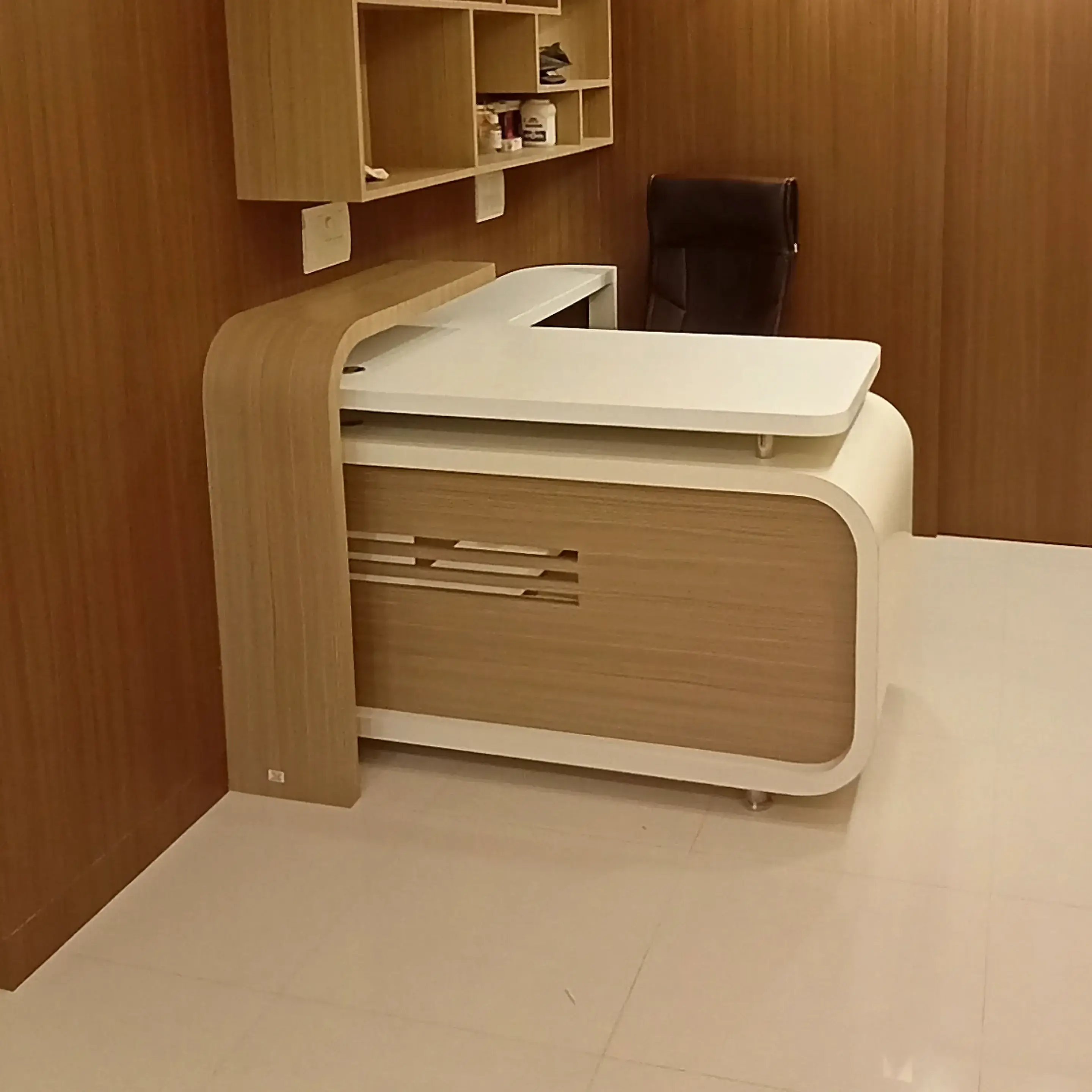 Curved white Corian reception desk with a walnut panel behind it